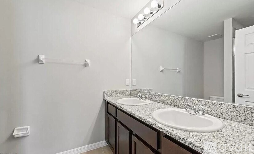 A bathroom with a granite countertop and a double sink vanity.