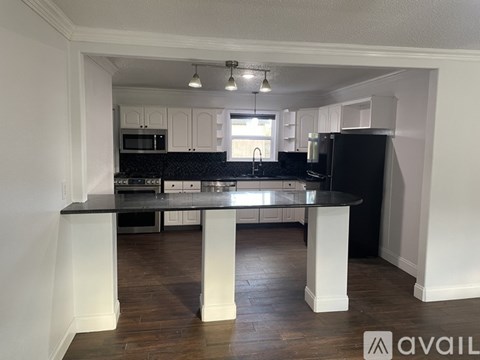 A kitchen with white cabinets and a black countertop.