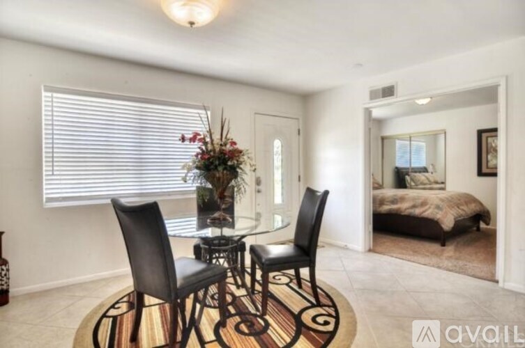 A room with a round table and two chairs in the foreground and a bedroom in the background.