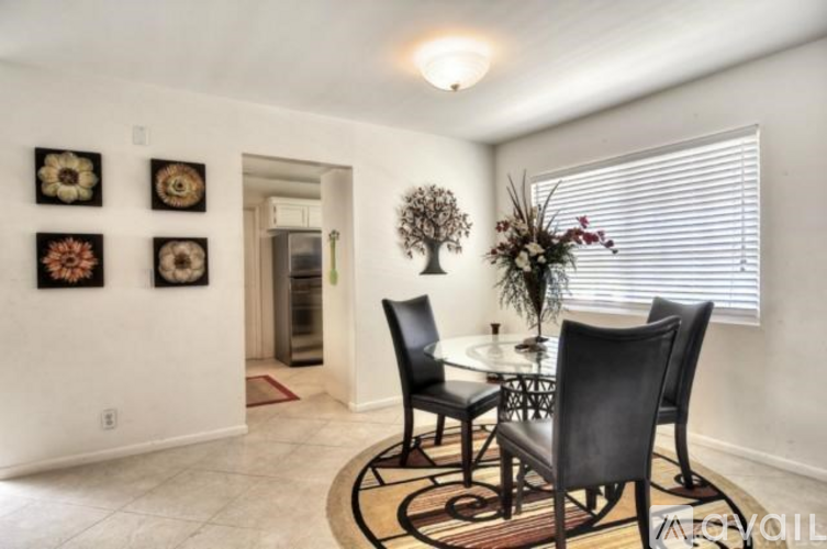 A dining room with a table set for two and a vase of flowers.