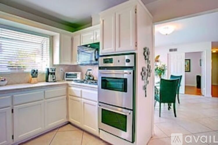 A kitchen with white cabinets and a green chair.