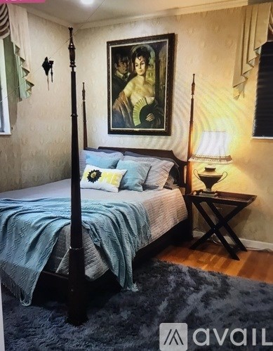 A bedroom with a four poster bed and a painting on the wall.