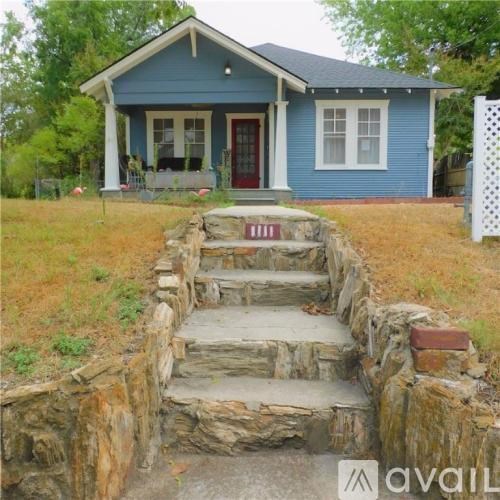 A blue house with a red door and a stone staircase leading to the front door.
