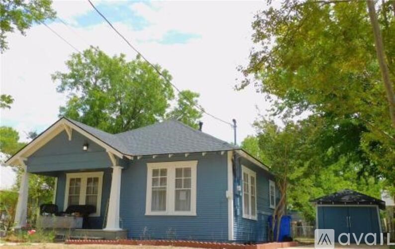 A blue house with a porch and a tree in front.