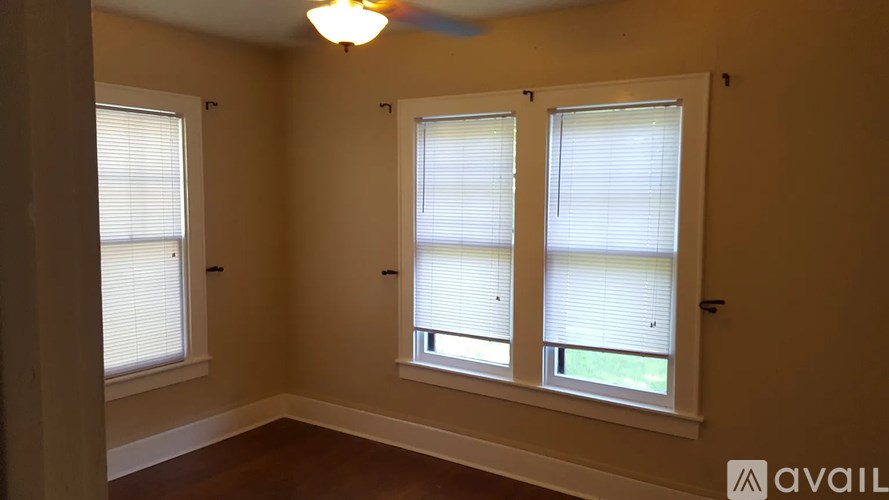 A room with a ceiling fan and three windows.