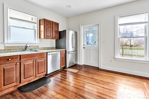 A kitchen with wooden cabinets and a black mat on the floor.