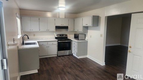 A kitchen with white cabinets and a wooden floor.