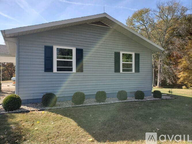 A house with a grey siding and a window with green shutters.