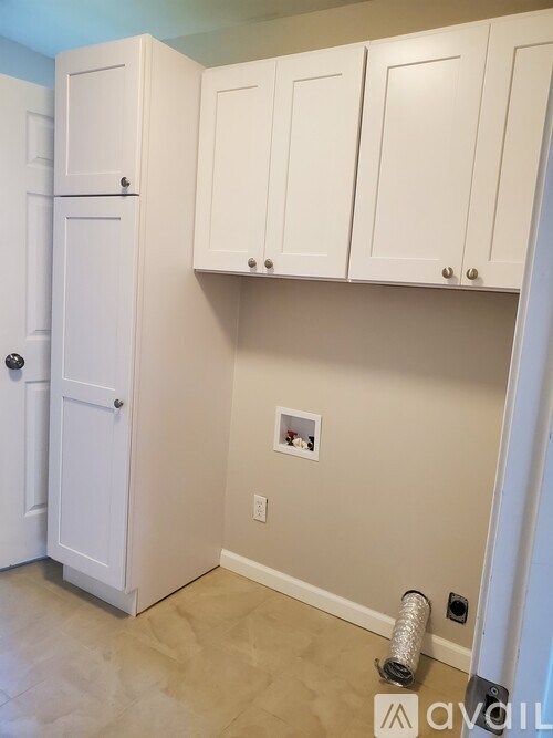 A white door is on the left and three white cabinets are on the right.