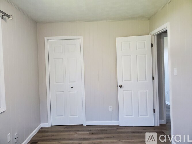 Two white doors in a room with wooden floors and white walls.