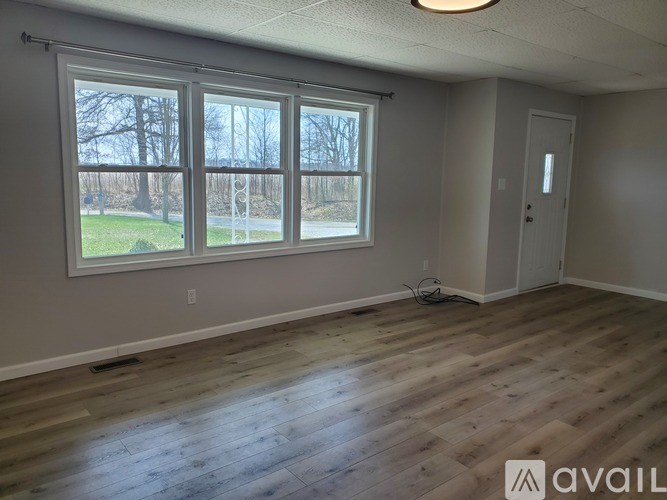 A room with a large window and wooden flooring.