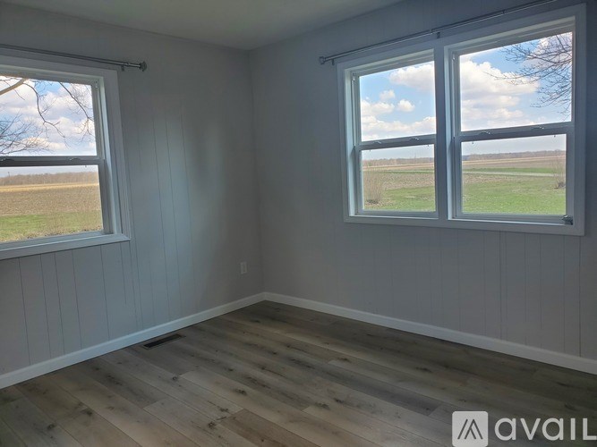 A room with a large window overlooking a field.