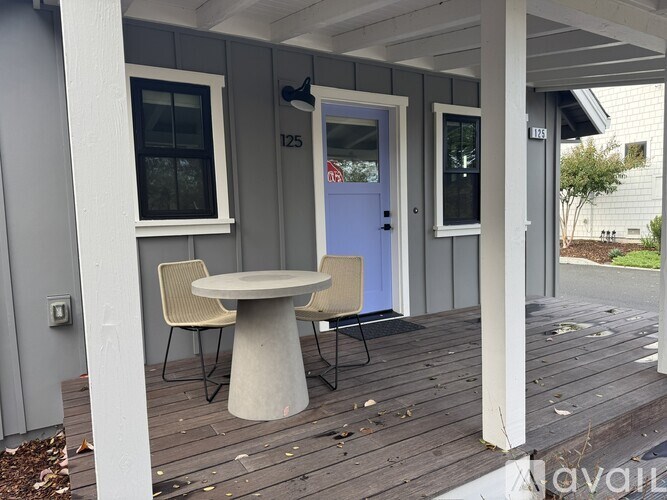 A small table with two chairs is on a porch.