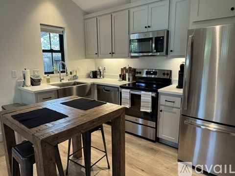 A modern kitchen with stainless steel appliances and wooden table.