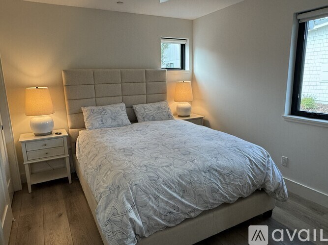 A bedroom with a bed, two lamps, and a nightstand.