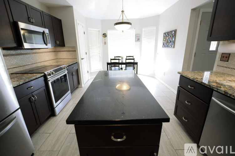 A kitchen with black cabinets and a black island in the middle.