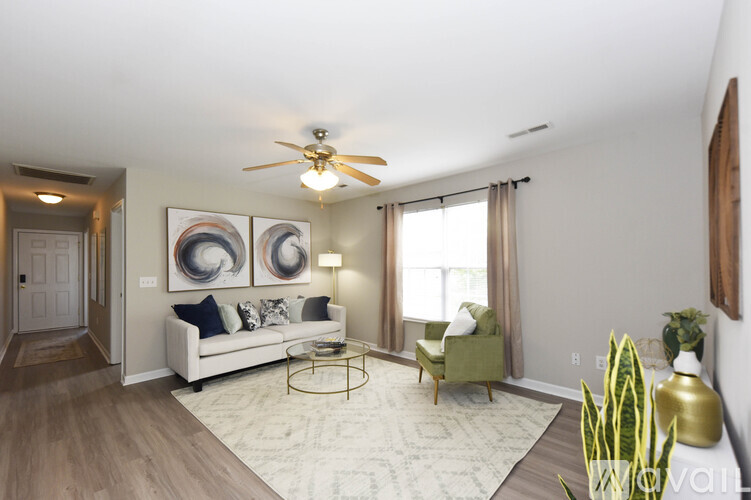 A living room with a white couch, a green chair, and a painting on the wall.