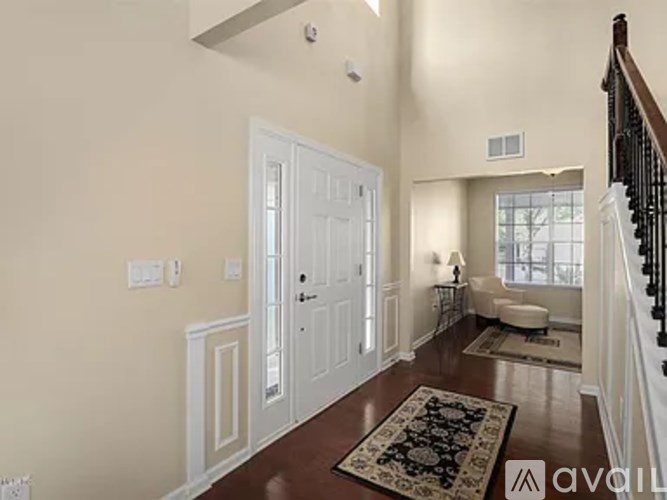 A hallway with a rug and a staircase.
