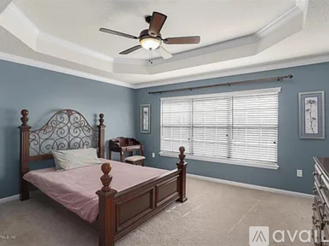 A bedroom with a bed, a chair, and a ceiling fan.