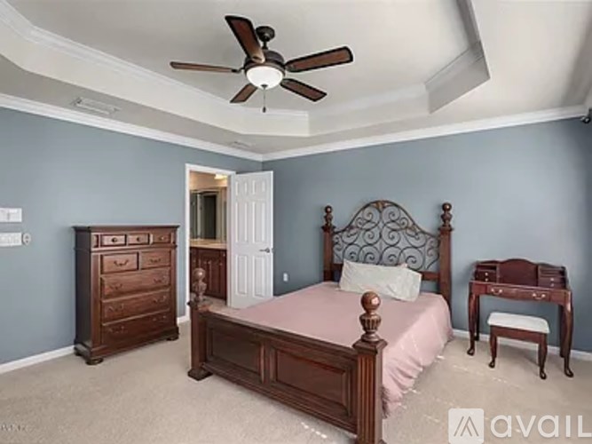 A bedroom with a bed, dresser, and desk.