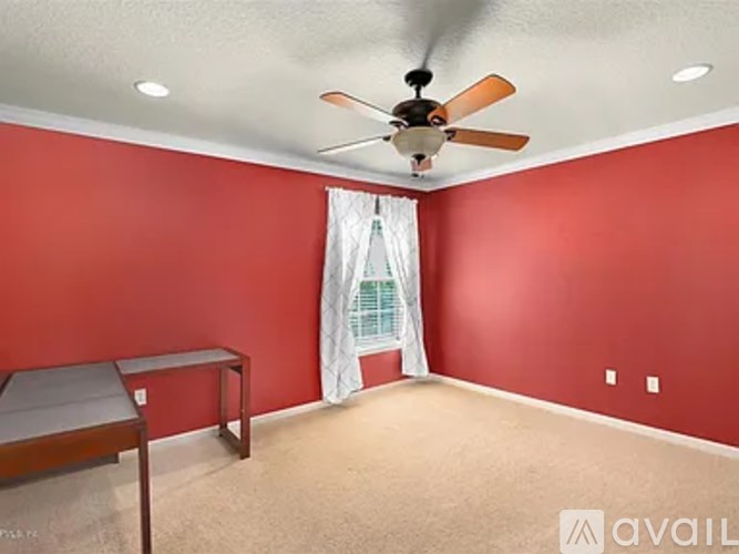 A room with red walls and a ceiling fan.