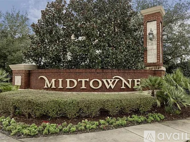 A sign that says Midtowne in front of a tree.