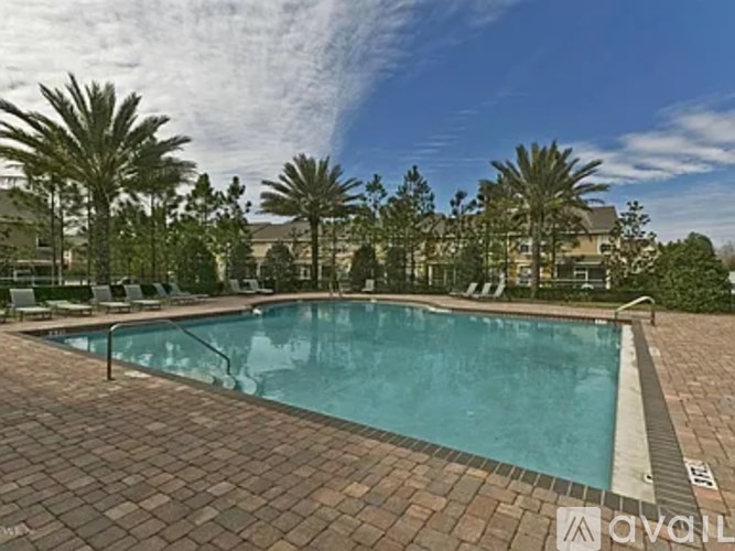 A pool surrounded by palm trees and a building in the background.
