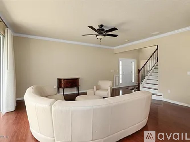 A living room with a white sofa and a ceiling fan.