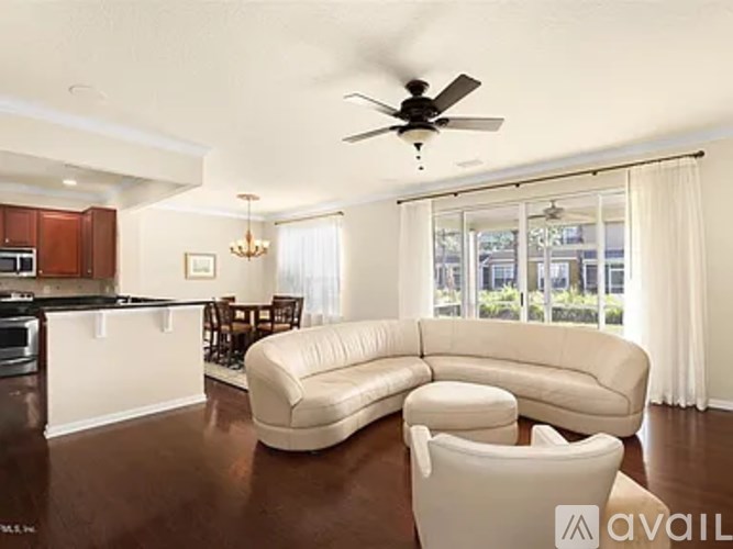 A modern living room with a white sofa and a ceiling fan.
