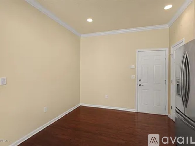 A room with a white door and a wooden floor.