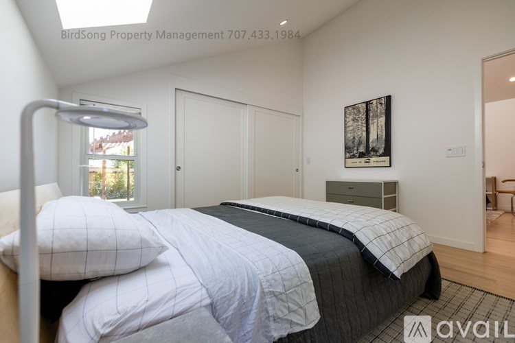 A bedroom with a bed, a lamp, and a picture on the wall.