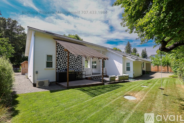 A white house with a black and white checkered awning is for sale.