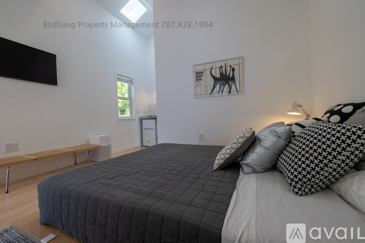 A bedroom with a large bed and a bench under a window.
