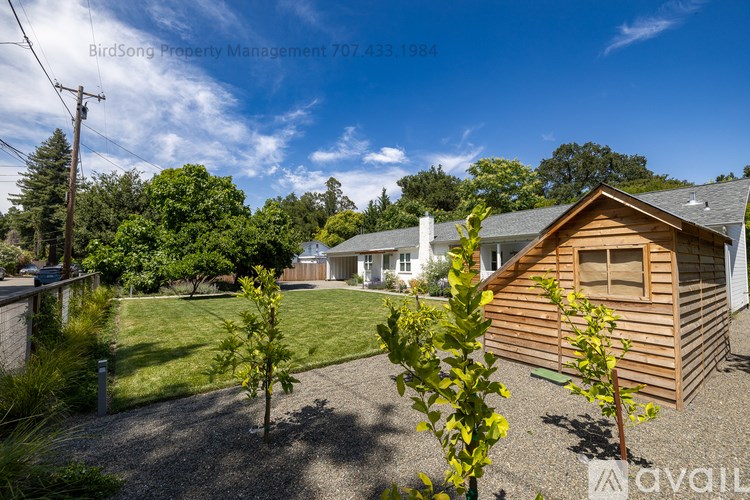 A house with a wooden exterior and a gravel driveway is for sale.