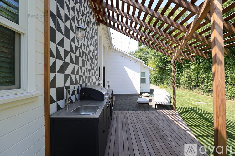 A wooden deck with a sink and a black and white tiled wall.