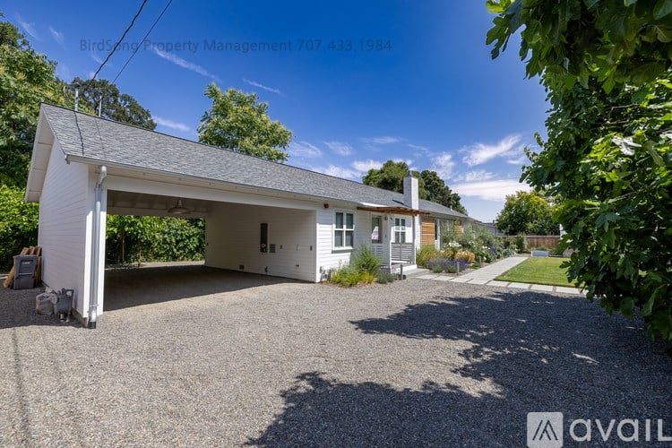 A white house with a gravel driveway in front of it.
