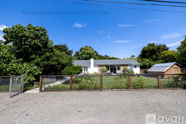 A house with a gravel driveway and a fence in front of it.