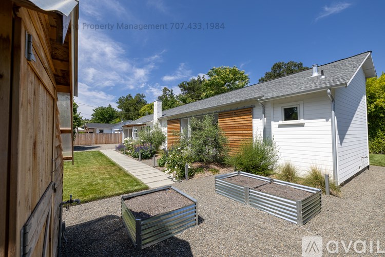 A sunny day at a property with a white house and a wooden fence.