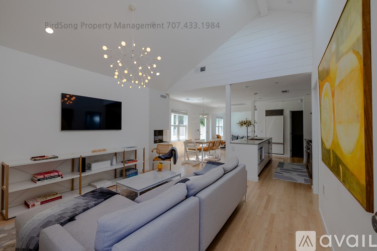 A living room with a grey couch and a television on the wall.