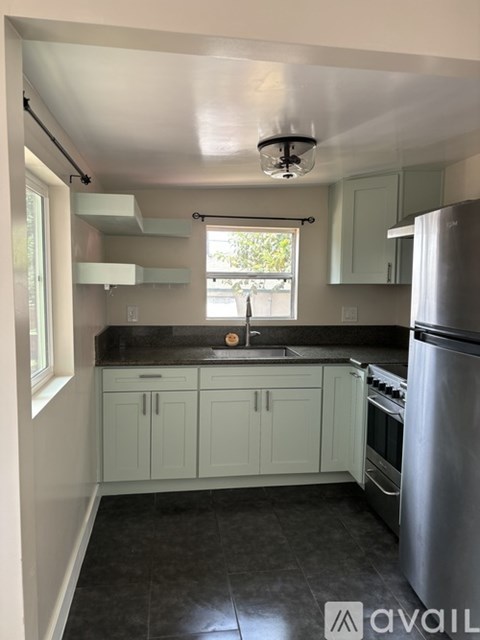 A kitchen with a stainless steel refrigerator and a window.