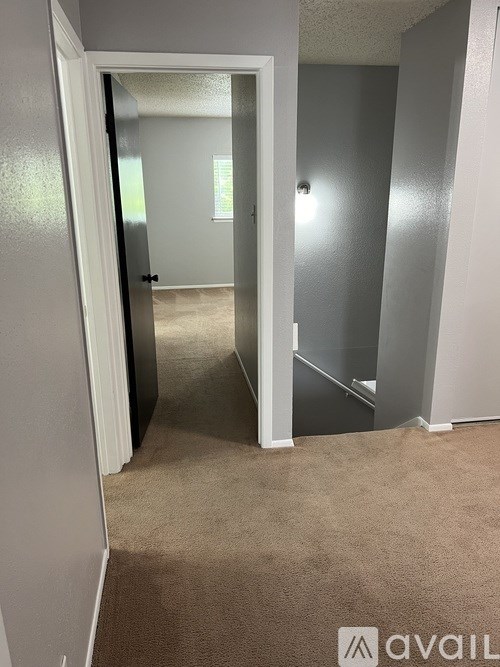 A hallway with a carpeted floor and a doorway leading to another room.