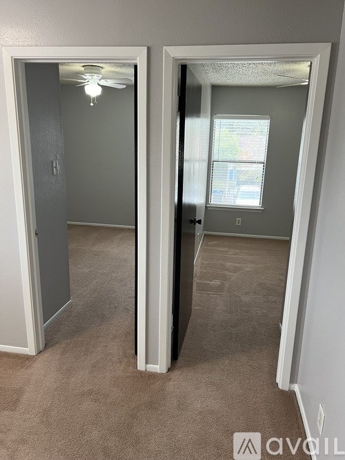 A room with a carpeted floor and a ceiling fan.