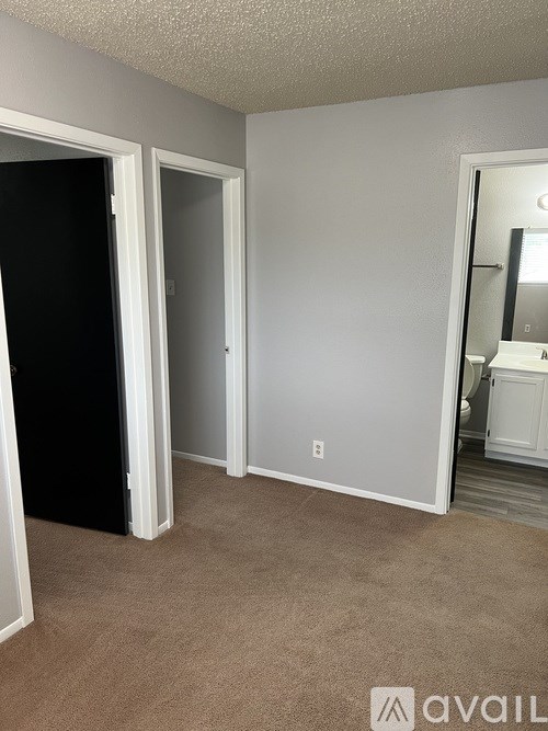 A room with a carpeted floor and a door leading to another room.