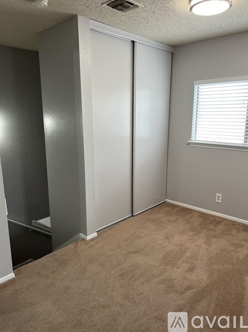 A room with a carpeted floor and a window with blinds.