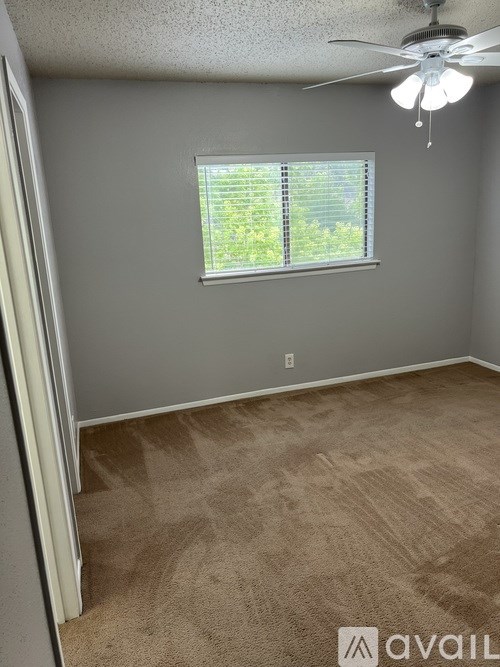 A room with a ceiling fan and a window with blinds.