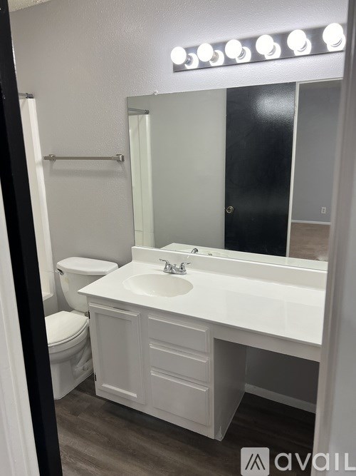 A bathroom with a white sink and a mirror with lights above it.
