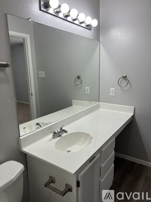 A bathroom with a white sink and a mirror with lights above it.