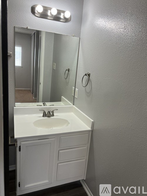 A bathroom with a white sink and a mirror with lights above it.