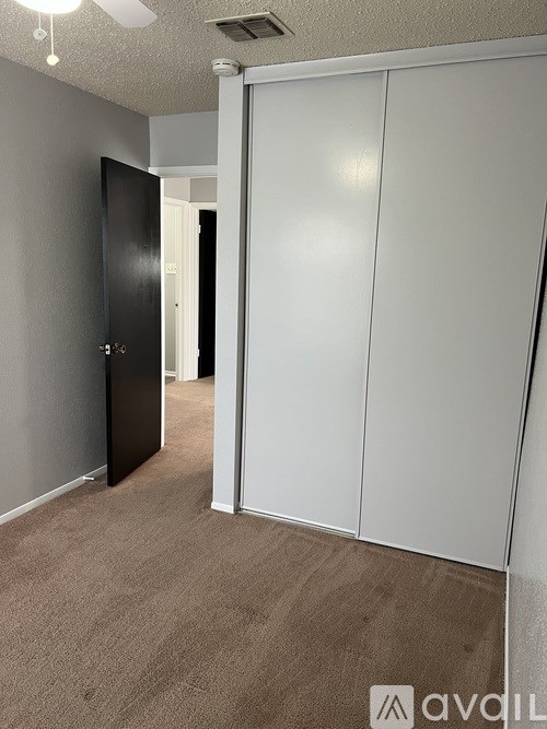 A room with a black door and white cupboards.