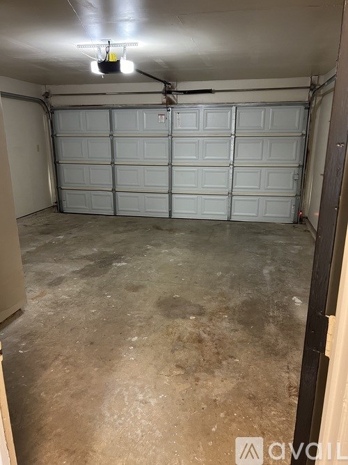 A garage with a white door and a fan on the ceiling.